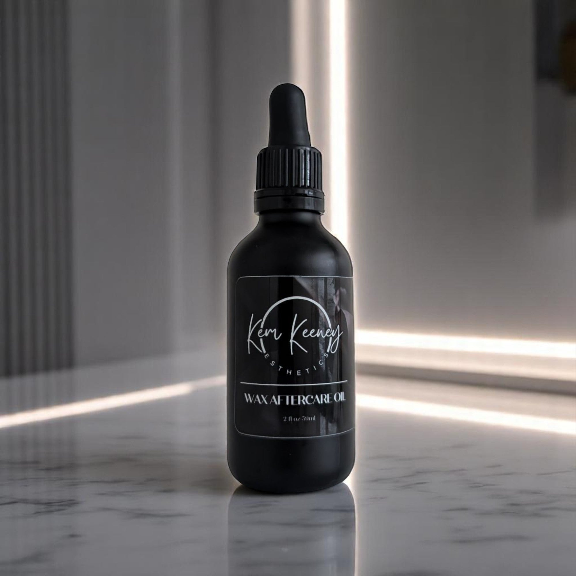 Black bottle with dropper labeled 'Kem Keeney Esthetics' on a marble surface.